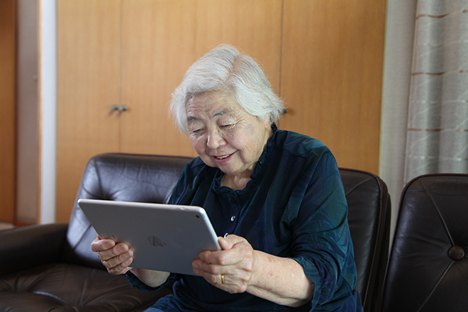 タブレットでツイッターや離れて暮らす家族とのコミュニケーションを楽しむミゾイキクコさん